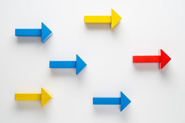 Wooden arrows on white background, one arrow in opposite direction from others. The concept of...