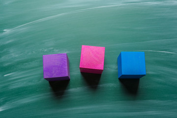 colored wooden cubes on green chalkboard