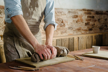 pottery, clay, ceramics art concept - closeup on hands of young master with the large pieces of fireclay