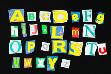 Colorful newspaper alphabet isolated on black