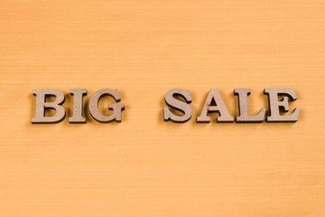 Word BIG SALE abstract wooden letters, background yellow silk texture