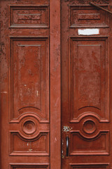 Closeup on an old and neglected wooden door with ironwork windows