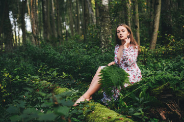 Beautiful girl in a dress in the forest among the fern.