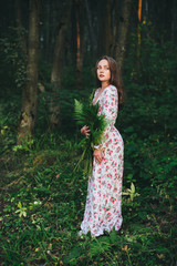 Beautiful girl in a dress in the forest among the fern.