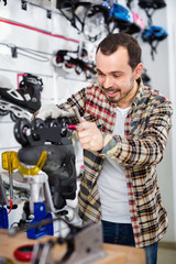 Male master fixing roller-skates in sports store