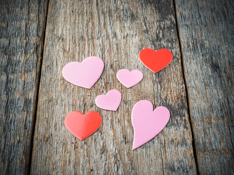 Decorations for Valentine's day pink and red paper hearts on a rustic wooden background
