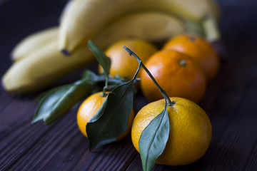 tangerines and bananas on a wooden table