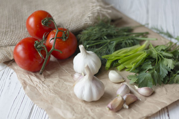 tomatoes, garlic and herbs on paper on a wooden table