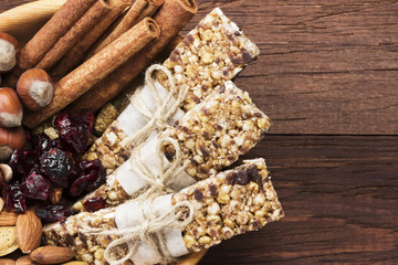 Cereal bars with nuts, berries and cinnamon on a wooden background. Top view, copy space. Food background