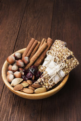 Cereal bars with nuts, berries and cinnamon on a wooden background
