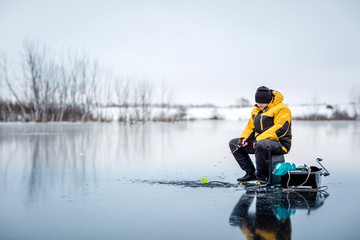 Man ice fishing on a frozen lake.