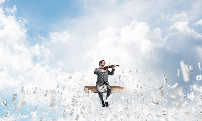 Handsome violinist play his melody and symbols fly around in air