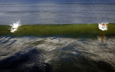 two surfers on cocoa beach riding the wave