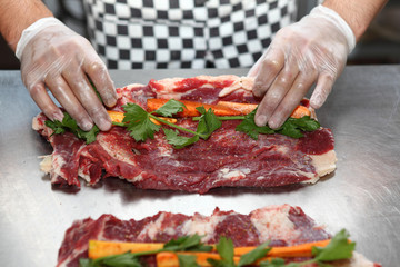 The cook puts vegetables into the meat and sprinkle with spices to prepare meat loaf.Uzbek cuisine.