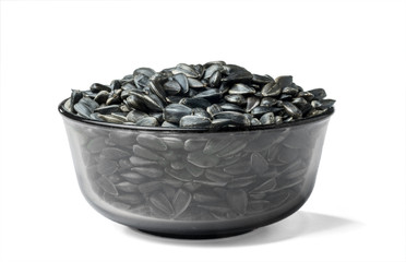 Glass bowl with sunflower seeds on a white background.