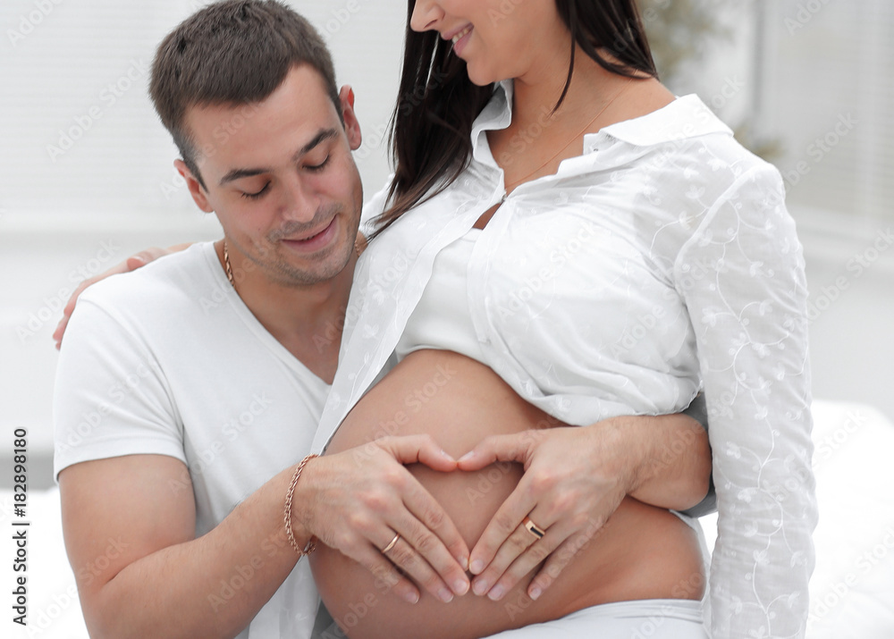 Wall mural closeup .husband and pregnant wife putting their hands on her tummy.