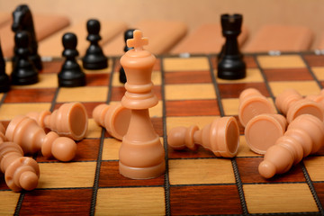 King figure on chessboard with pawns laying down Winning concept