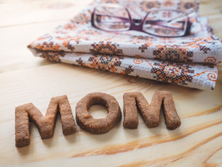 Word Mom biscuit over the wood background. The concept of a single parent.

