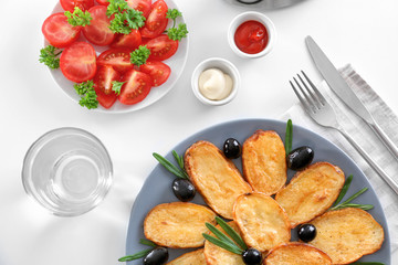 Composition with plate of delicious baked rosemary potatoes on table