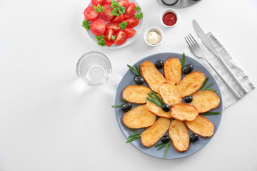 Composition with plate of delicious baked rosemary potatoes on table