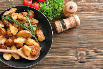 Composition with pan of baked rosemary potatoes on wooden table