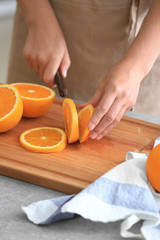 Woman cutting ripe orange in kitchen