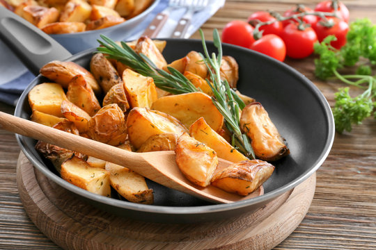 Pan with delicious rosemary potatoes on wooden table