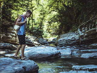 man standing on the mountain canyon river stream with backpack
