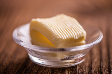 close up butter in a dish  on old wood background