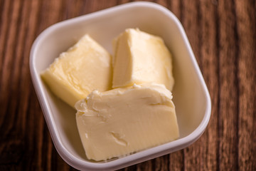 close up butter in a dish  on old wood background