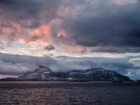 Insel mittem im Meer bedeckt von einer Wolkendecke in Sonnenuntergangsstimmung