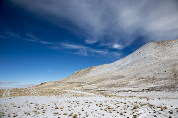Зимний пейзаж. Красивые горы в снегу, белые облака на синем небе над живописным ущельем. Припрда Северного Кавказа