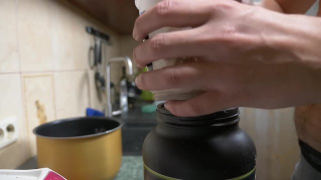 Slow motion. 4k. Young man making a protein shake at home. anonymously