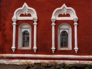 Red brick wall of monastery with white windows