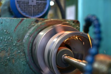 metalworking industry: finishing metal working on lathe grinder machine with flying sparks