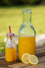 freshly sqeezed orange juice in a glass bottle outdoor shot in a garden
