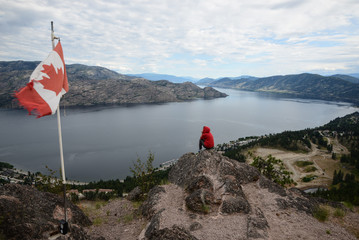 Girl standing in top of a mountain with a red hoodie in Peachland British Columbia, Canada