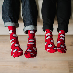 Feet in woollen socks. Pair relaxing with a cup of hot drink and warming up their feet in woollen socks. - 182909176