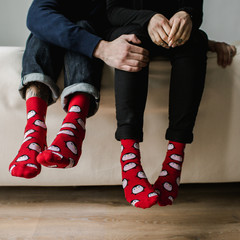 Feet in woollen socks. Pair relaxing with a cup of hot drink and warming up their feet in woollen socks. - 182909367
