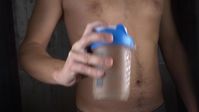 Slow motion. 4k. Young man making a protein shake at home. anonymously