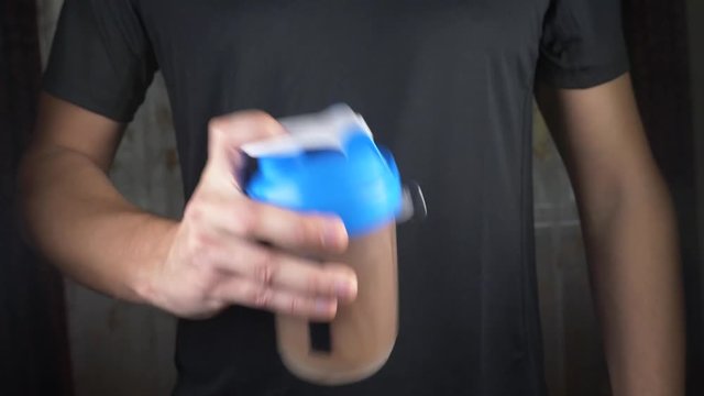 Slow motion. 4k. Young man making a protein shake at home. anonymously