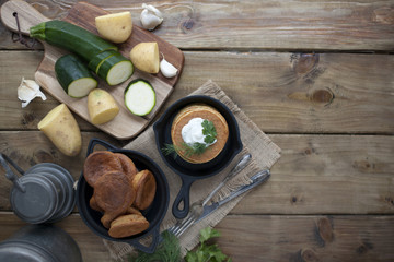 pancakes from vegetables in a cast-iron frying pan on a wooden background