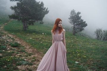 Fototapeta premium 2043679 Young beautiful woman in a long blue dress in the mountains near the trees