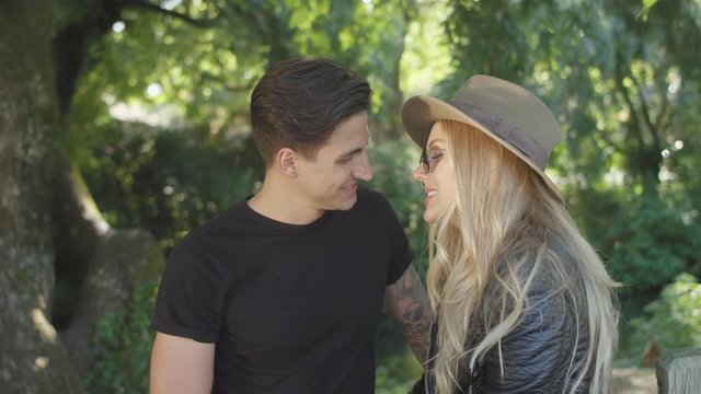 Young attractive couple joke and flirt with each other at a park, Lens flare