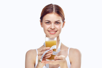 2043755 Young woman holding orange juice and measuring tape on a light background, diet