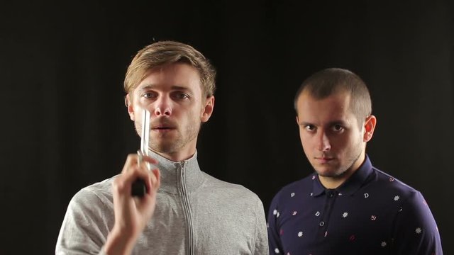 Two young funny criminal hipster men with fake gun