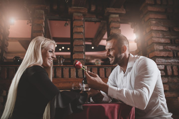 Young couple in love on a romantic evening. He gives her a rose.