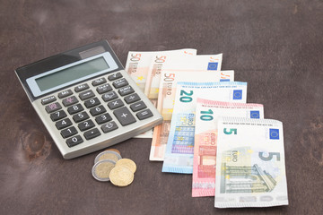 Banknotes and coins with calculator. Euro banknotes on wooden background. Photo for tax, profit and costing. 50 euro, 20 euro, 10 euro. Money and finance