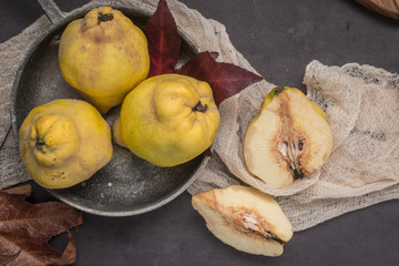 Quince fruits and marmelade in a ceramic bowl on table top.