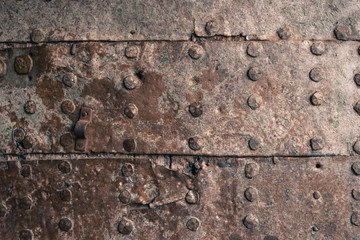 Rusty metal texture. Studded iron plate. Rivets on old rusty metal door. Weathered aged grunge...